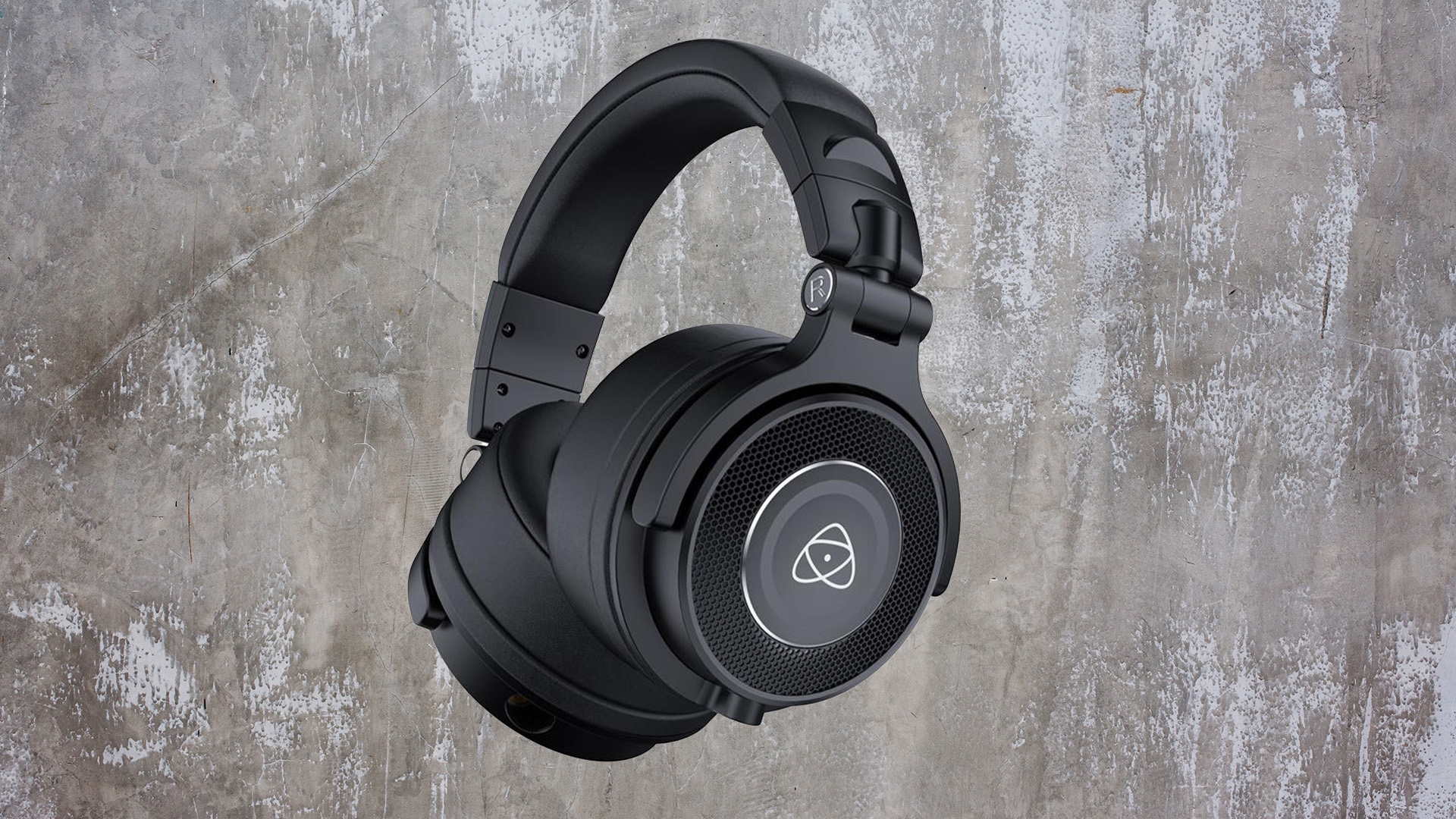 A pair of black Studiosonic Production Headphones in front of a grey and greenish stone background